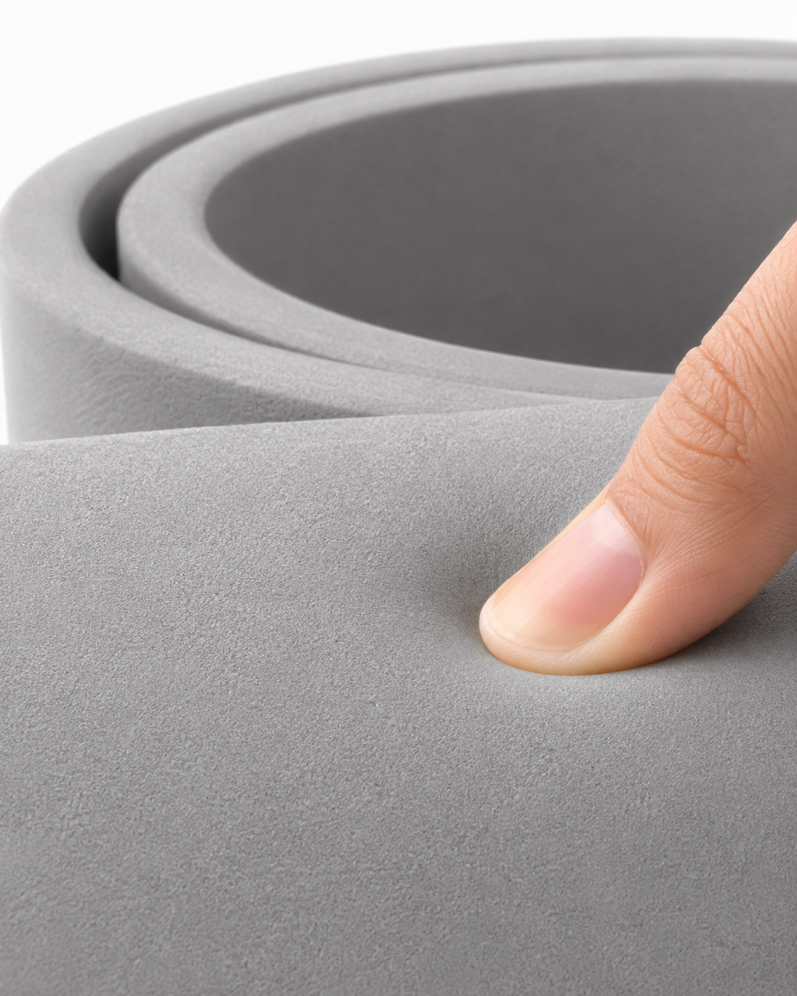 Fingertip pressing into the grey cushioning foam, showing how the surface gives under pressure.