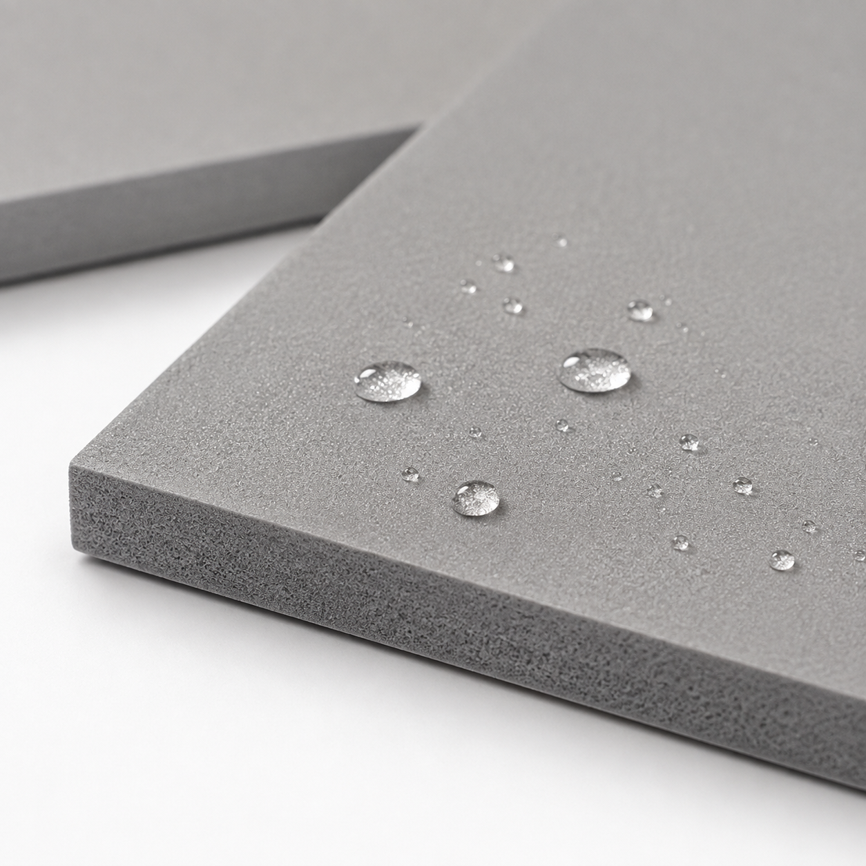 Close view of the grey cushioning surface with water beading on top.